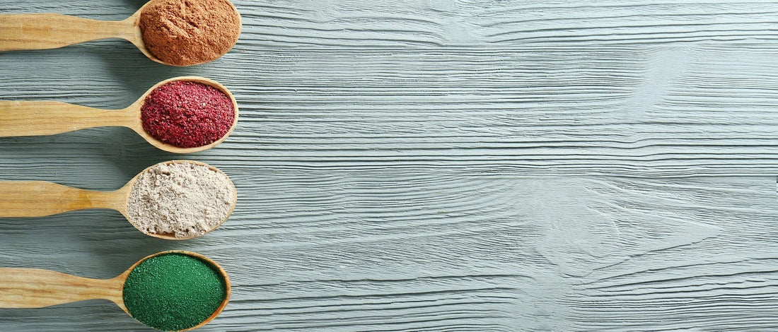 Chlorella powder and other supplements in wooden spoons