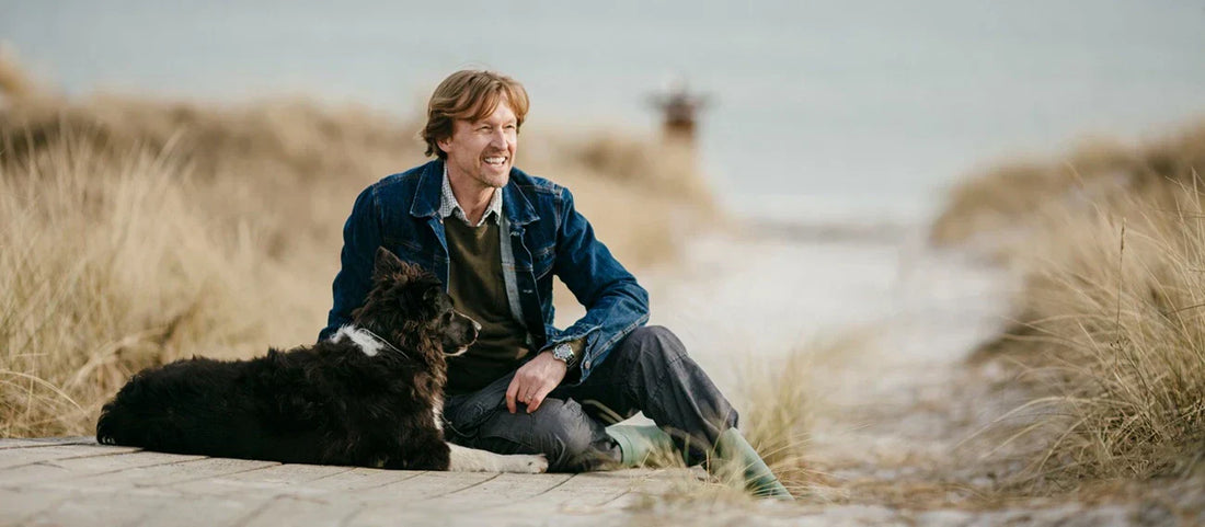 Man sitting with his dog in a calm space close to the sea