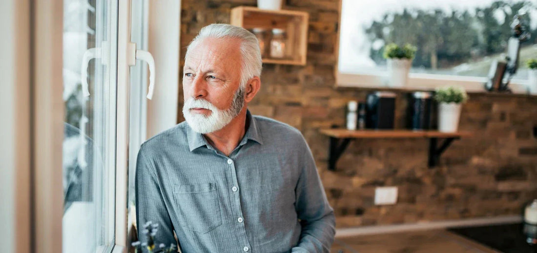 Senior man looking through window on winter in Canada