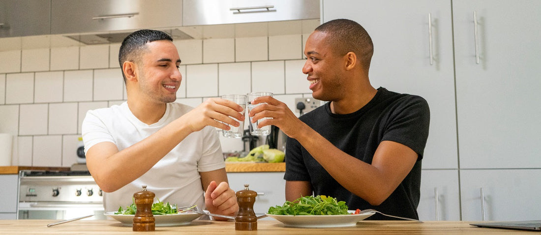 Two men drinking water and eating salad