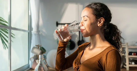 Woman drinking water with supplements in the kitchen