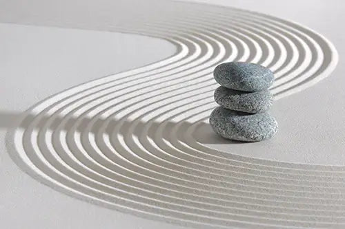Stack of stones on a sandy surface with circular patterns